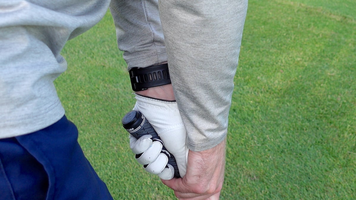 Shot Scope V3 golf watch on wrist with club tracking tag in close proximity.