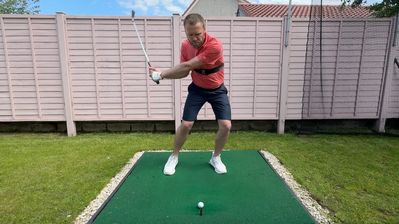 Andy hitting an iron whilst wearing the TRS Slider swing training aid.